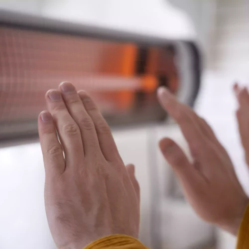 close-up-people-warming-up-hands-near-heater